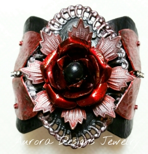 Matte black and Glossy red with a black pearl center and rhinestone cup chain accent. Pearl Ex powder on the focal swirled edges and the outside flower petals.